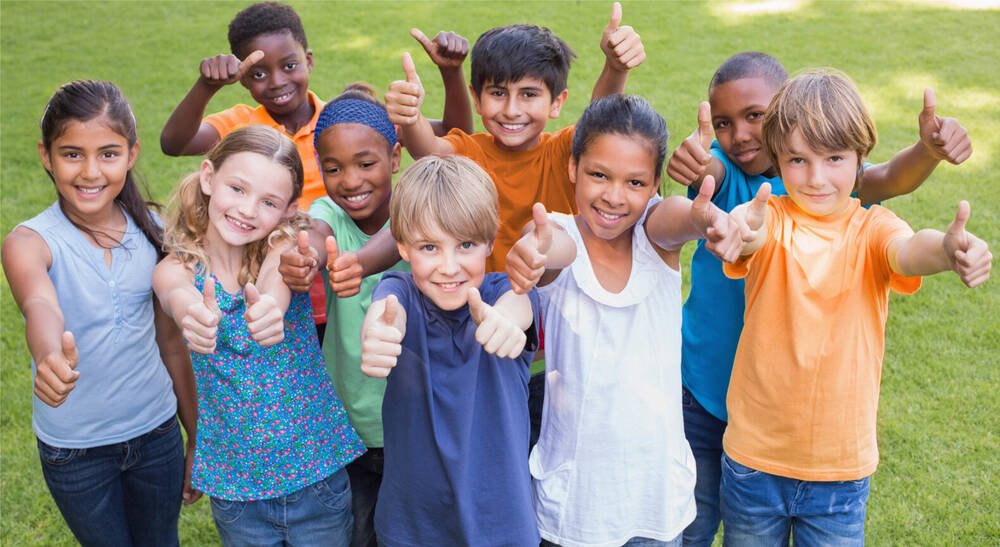 Group of children outdoors giving thumbs up